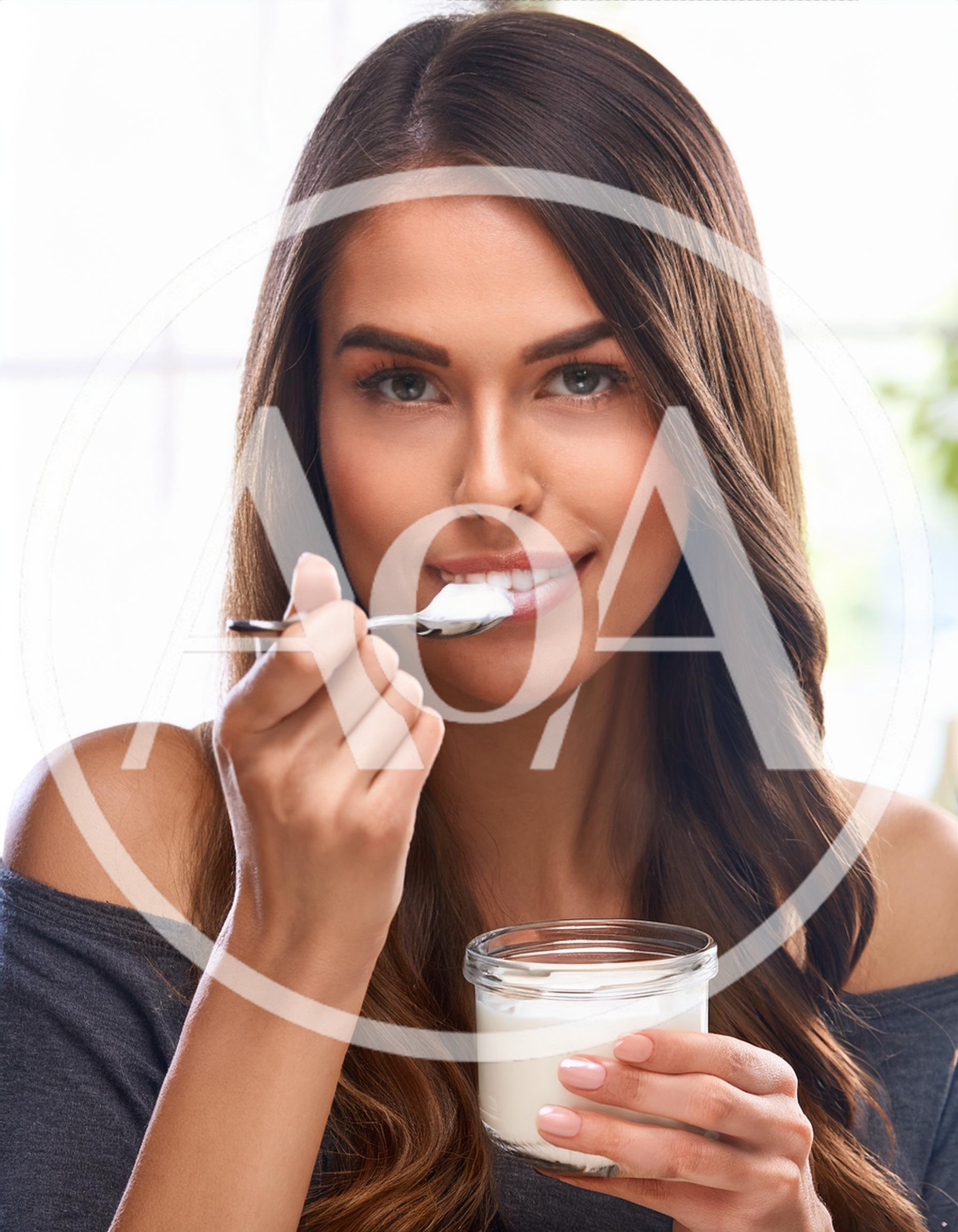 Young Woman Eating Yogurt From A Glass Jar
