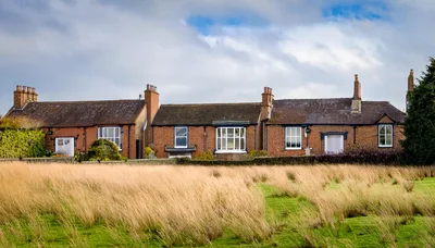 Row Of Traditional English Brick Cottages In Rural Landscape