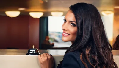 Smiling Hotel Receptionist Standing Behind The Front Desk