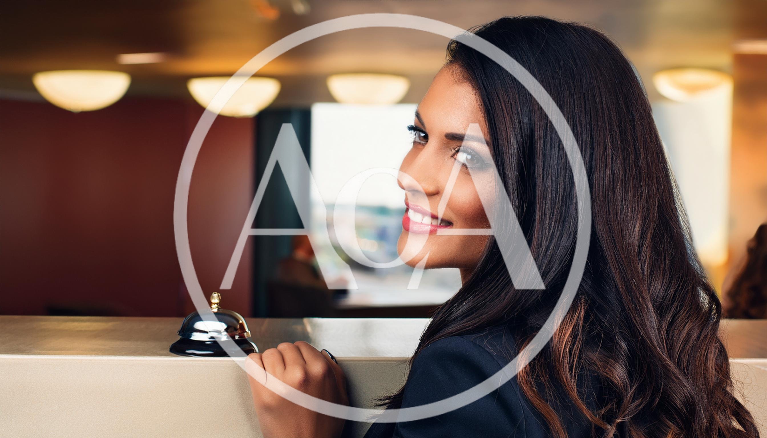 Smiling Hotel Receptionist Standing Behind The Front Desk