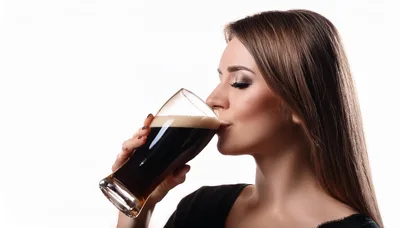 Young Woman Drinking Dark Beer From A Glass