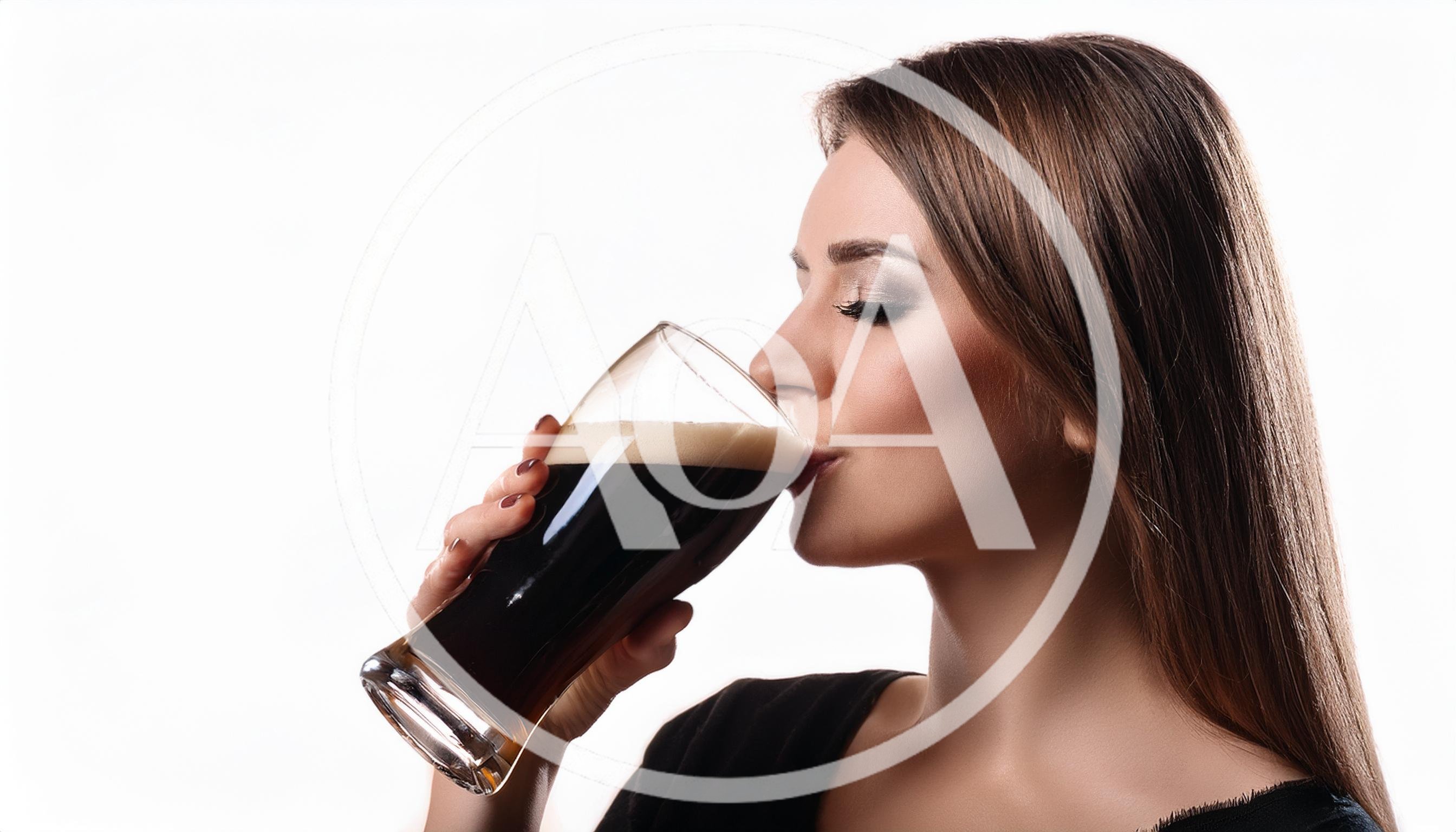 Young Woman Drinking Dark Beer From A Glass