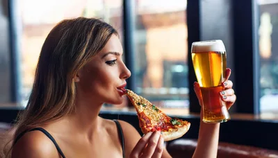 Young Woman Eating Pizza And Drinking Beer