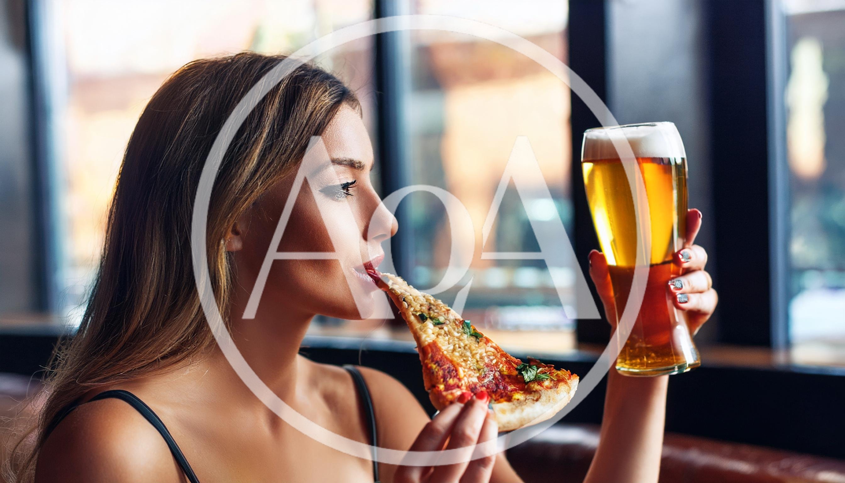 Young Woman Eating Pizza And Drinking Beer