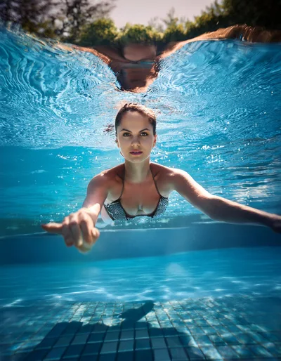 Young Woman Swimming Underwater In A Sunny Pool