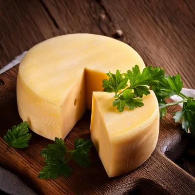 Wheel Of Sliced Cheese On Wooden Board