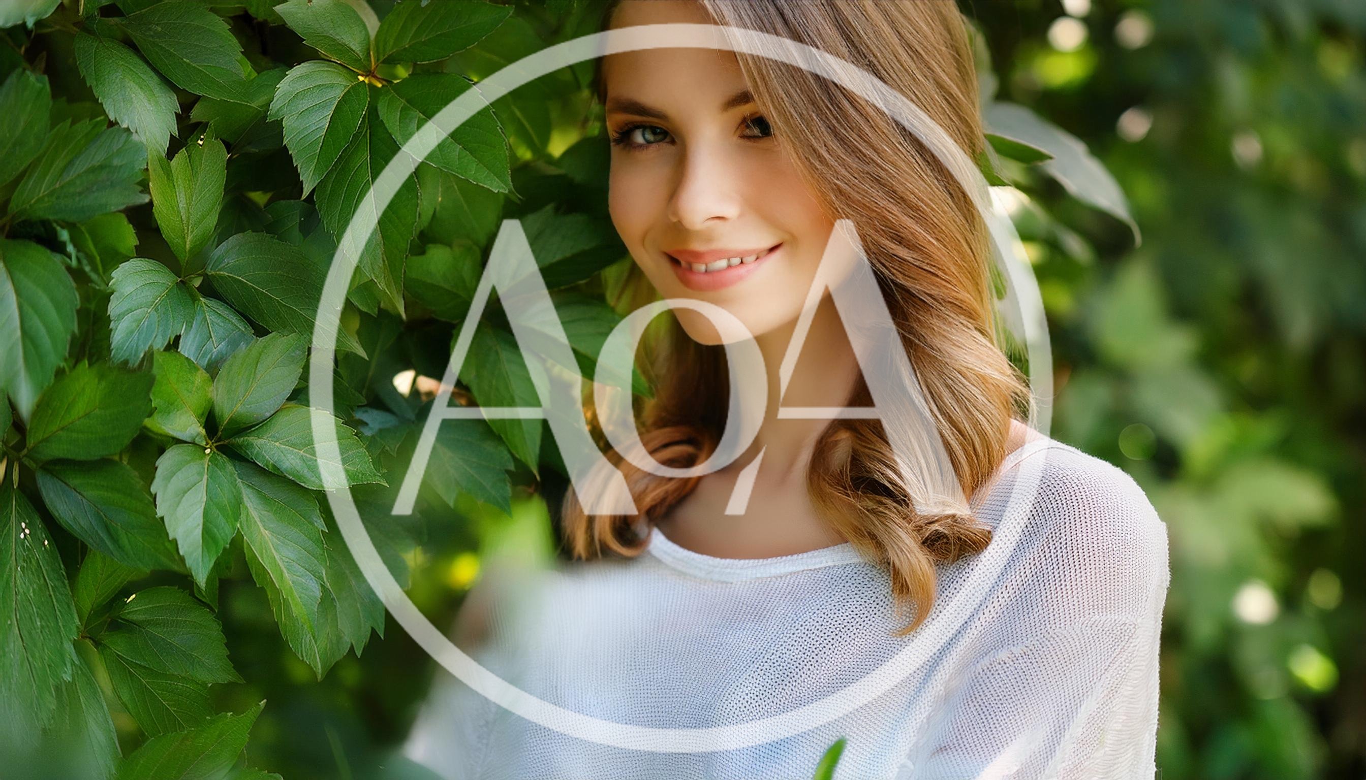 Young Woman Smiling Outdoors Near Green Foliage