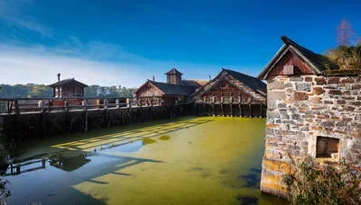 Historic Wooden Water Mill Structures On A Green Pond
