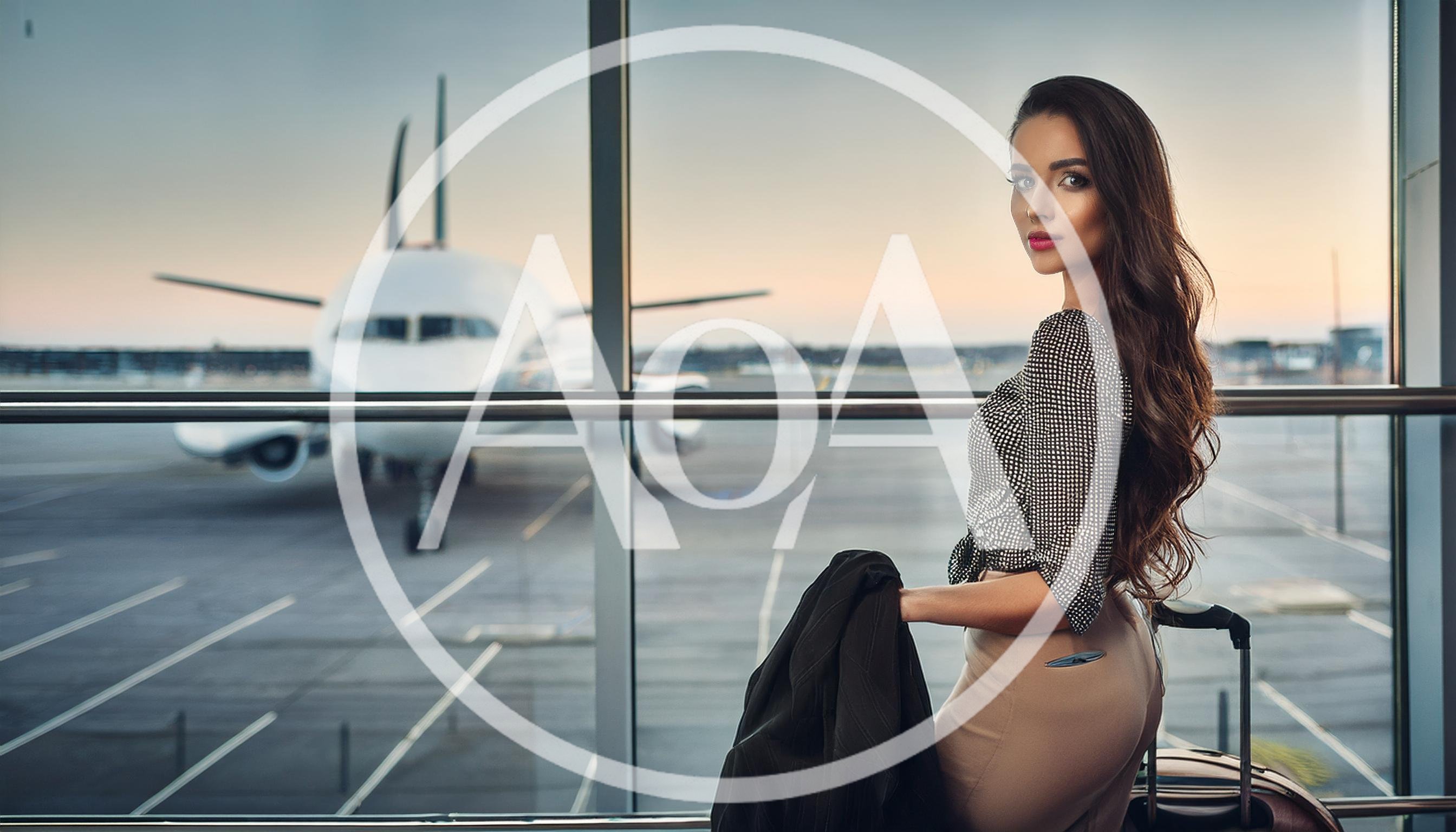 Elegant Woman Standing With Luggage At Airport Terminal