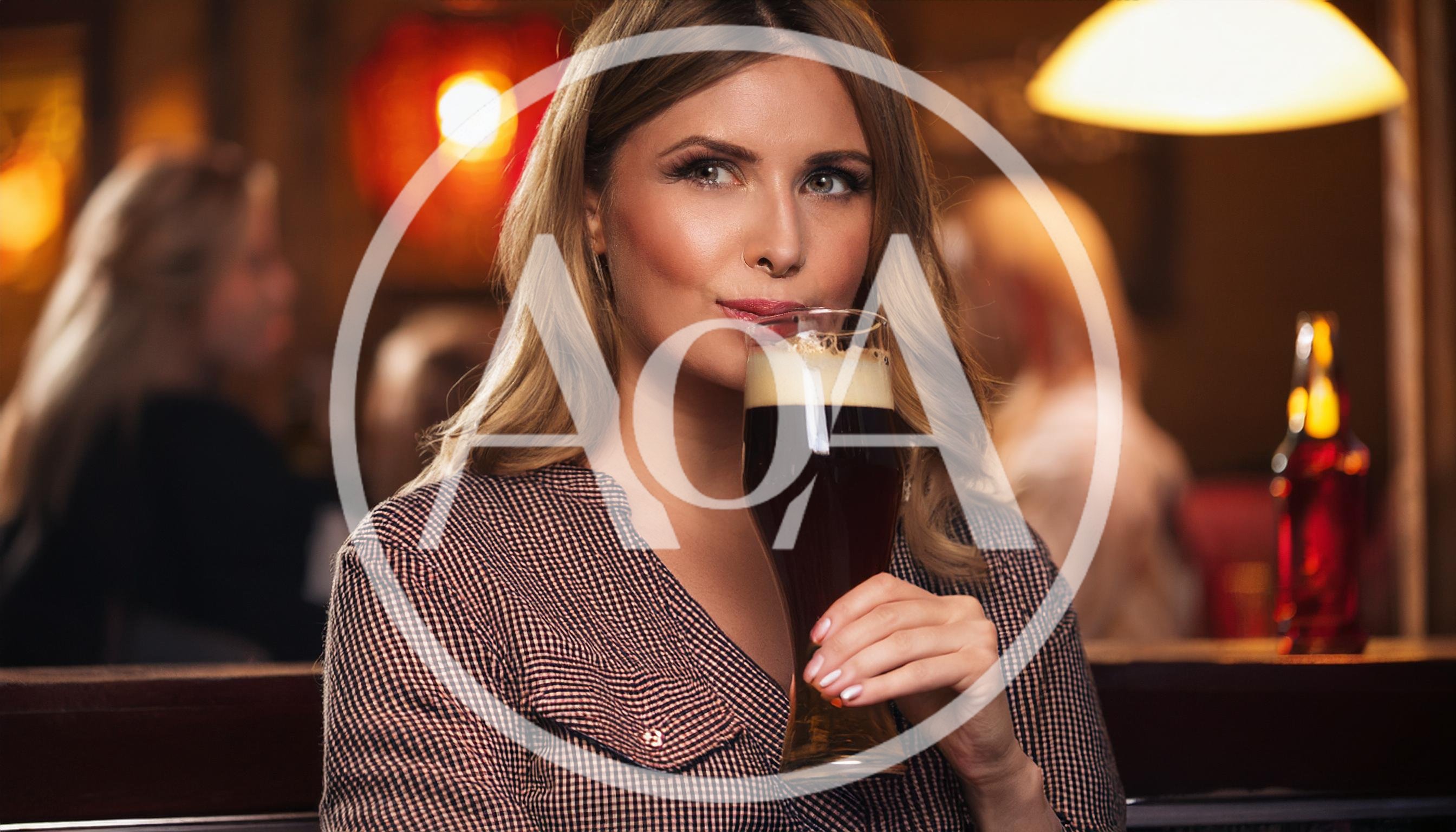 Young Woman Drinking Dark Beer in a Pub
