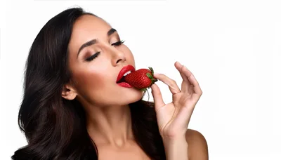 Beautiful Woman Holding A Fresh Strawberry To Her Lips