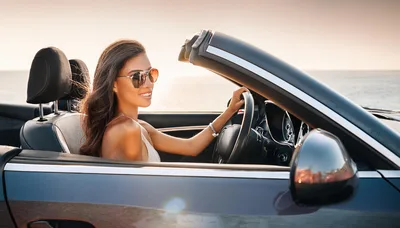 Young Woman Driving A Convertible Car At Sunset