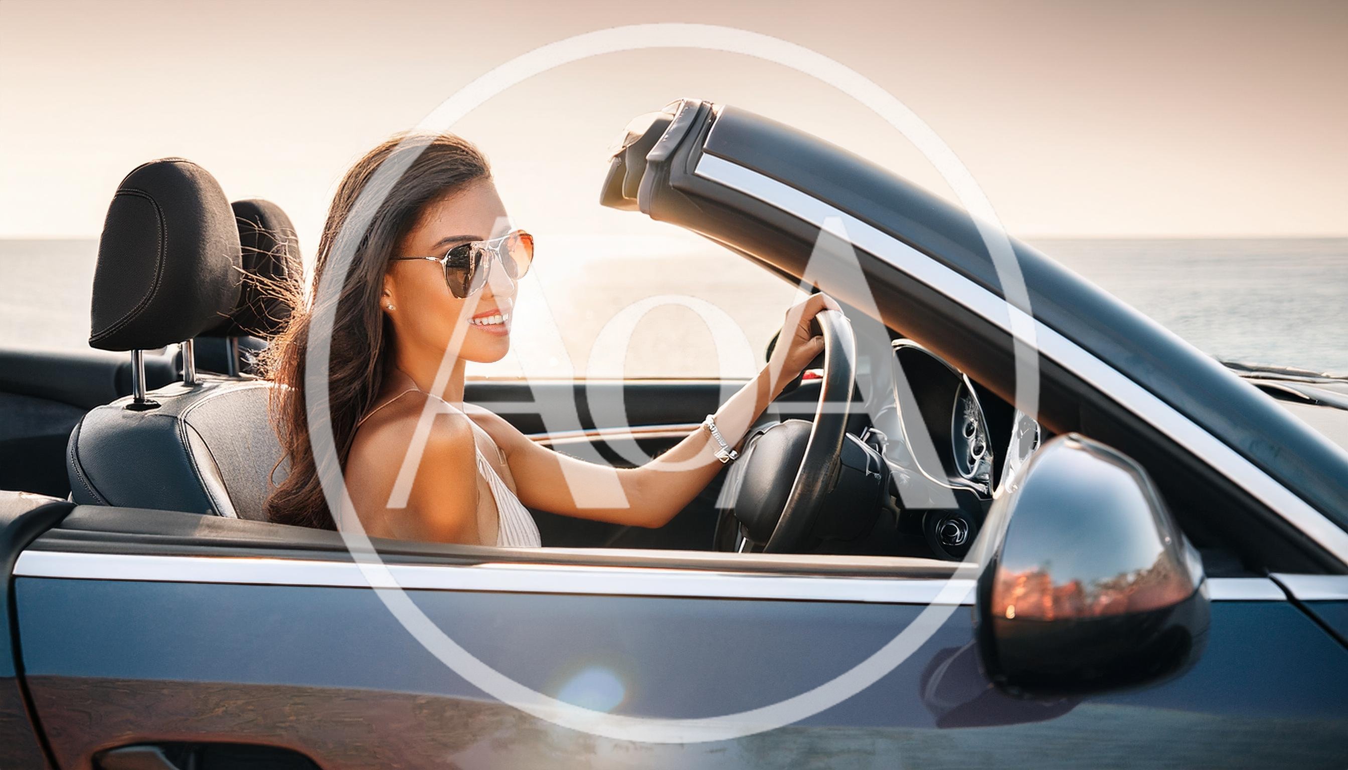 Young Woman Driving A Convertible Car At Sunset