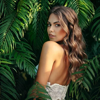 Beautiful Woman Posing Amidst Lush Tropical Palm Leaves