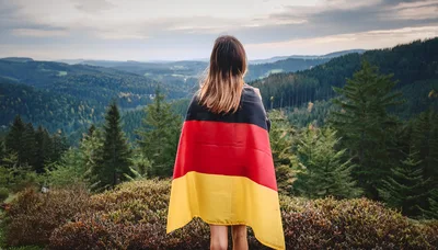 Woman Standing With German Flag Overlooking Forest Landscape