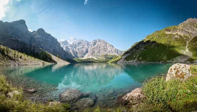 Panoramic View Of Turquoise Alpine Lake And Mountains