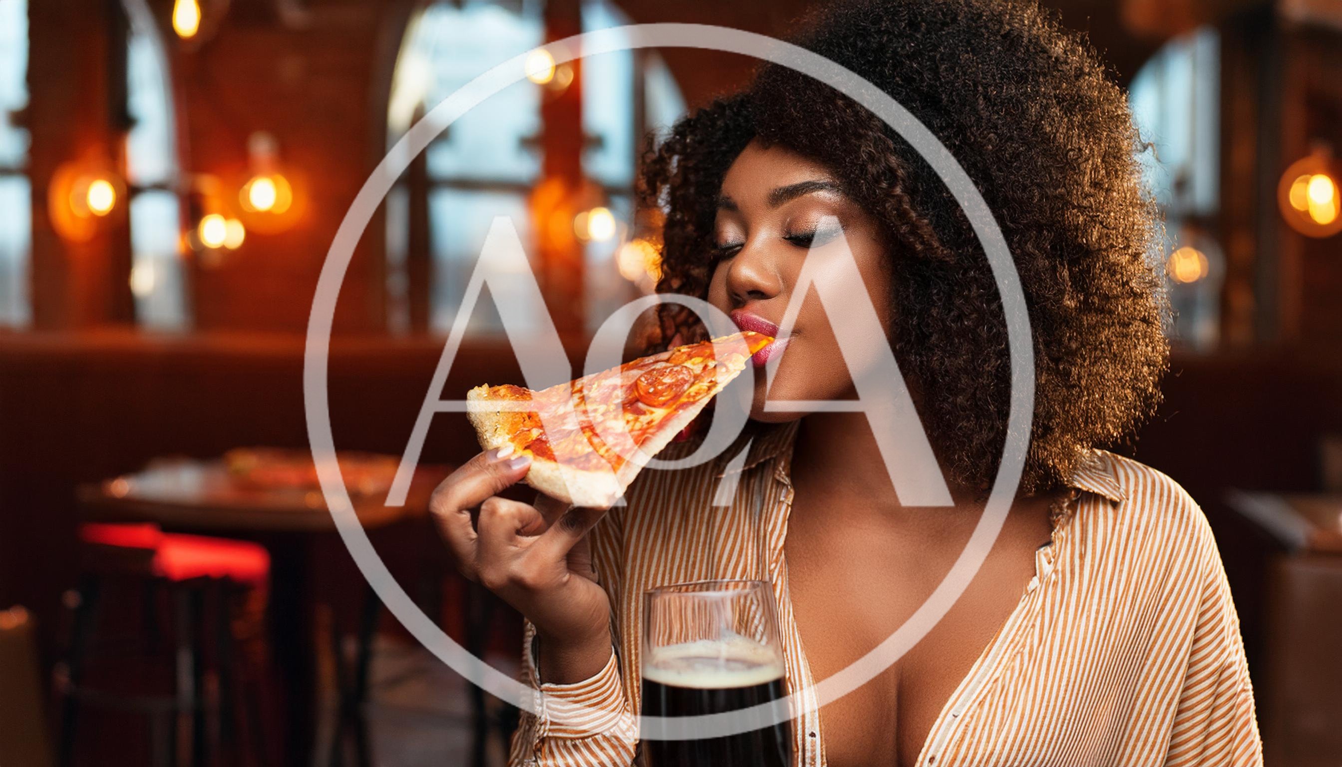 Young Woman Eating Pizza Slice In A Restaurant
