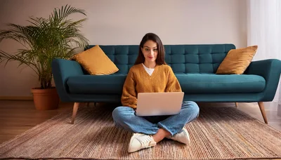 Young Woman Working on Laptop Sitting on Living Room Floor