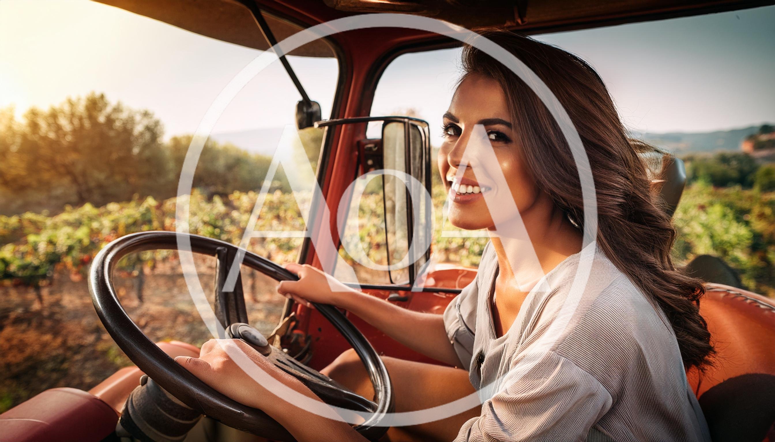Smiling Woman Driving A Tractor Through A Vineyard