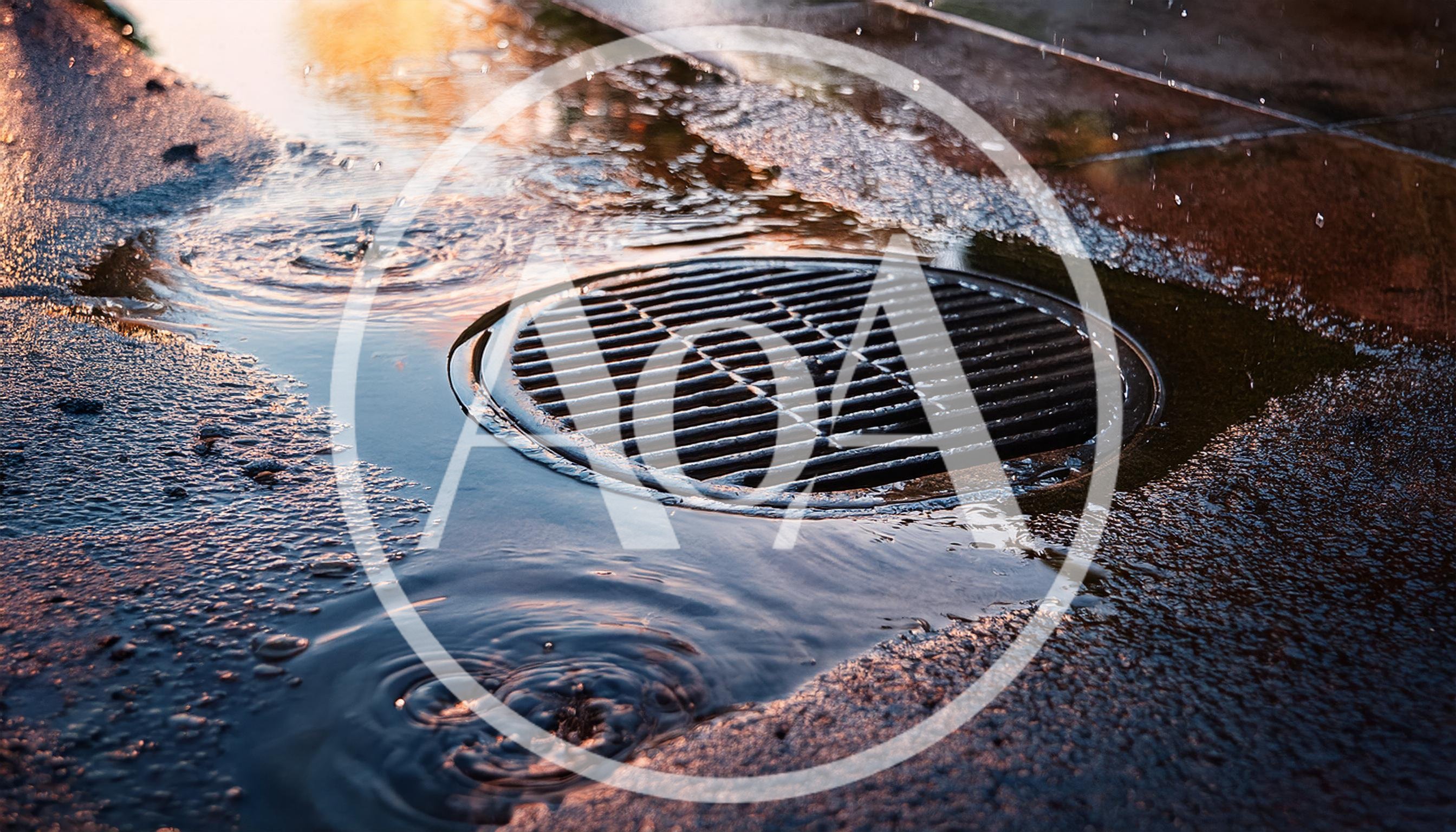 Raindrops Falling Into A Storm Drain On Asphalt