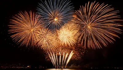 Vibrant Golden And Blue Fireworks Display Over Water