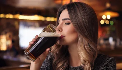 Young Woman Drinking Dark Beer In A Pub