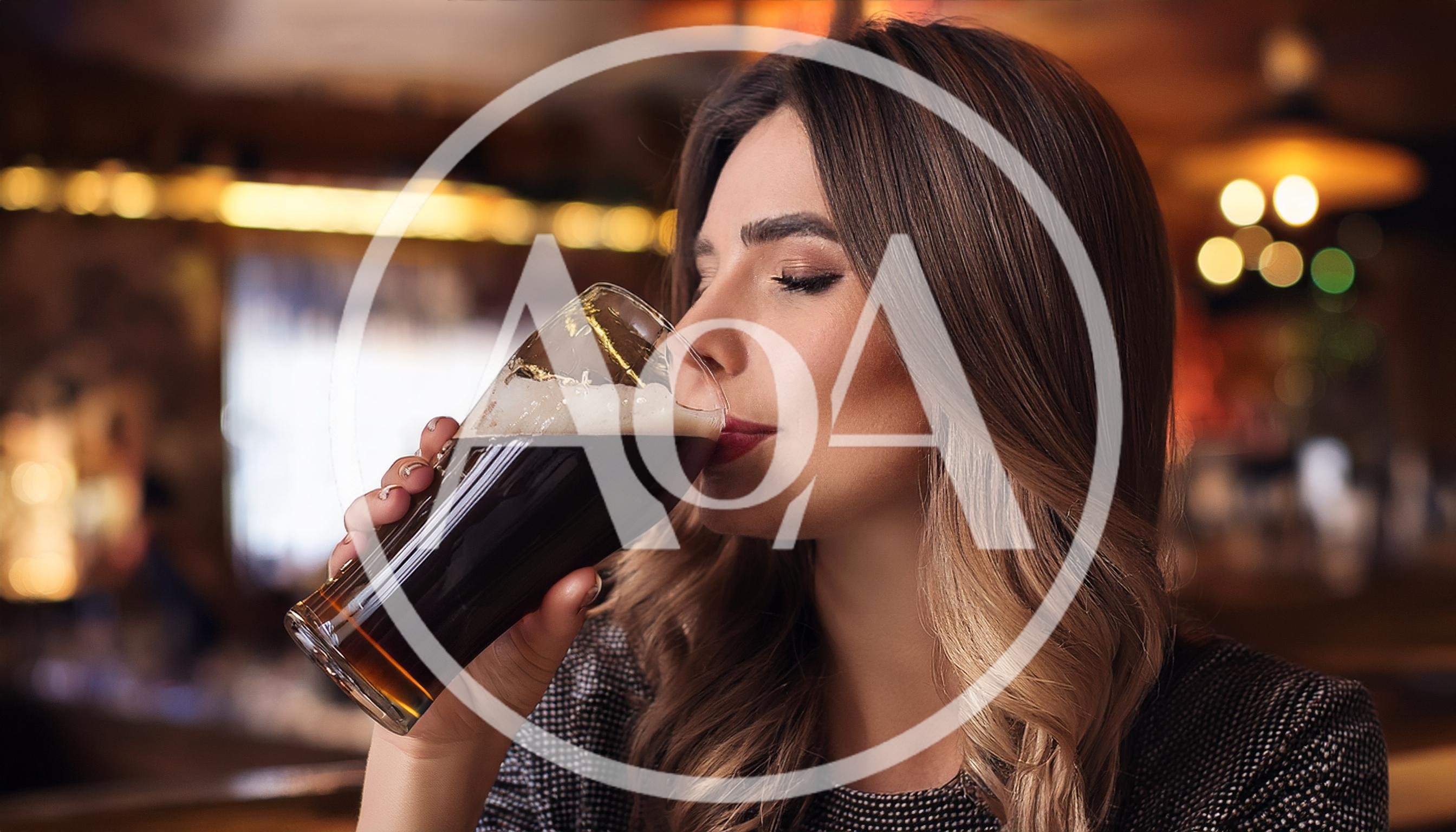 Young Woman Drinking Dark Beer In A Pub