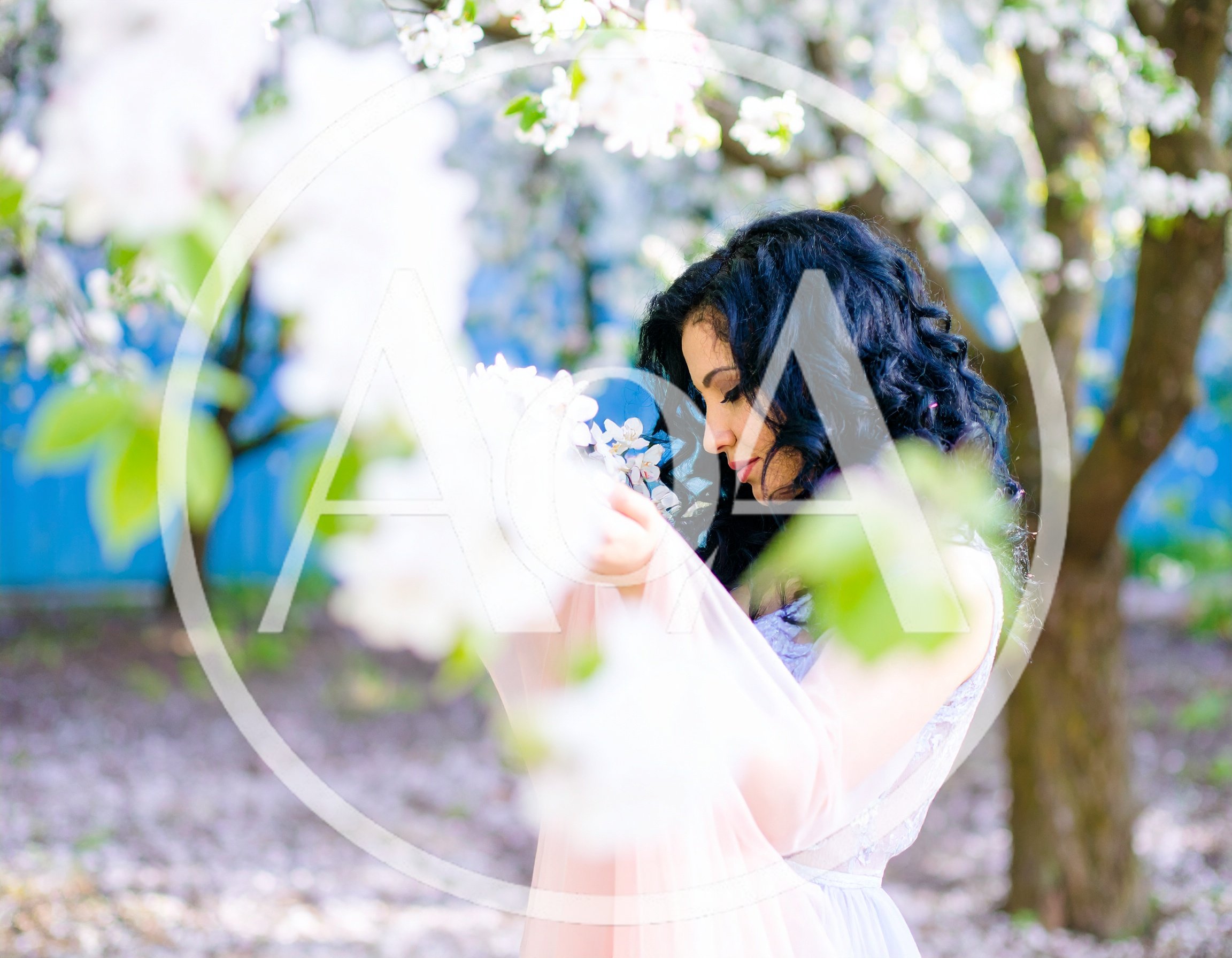 Woman With Curly Hair Posing In Blooming Apple Orchard
