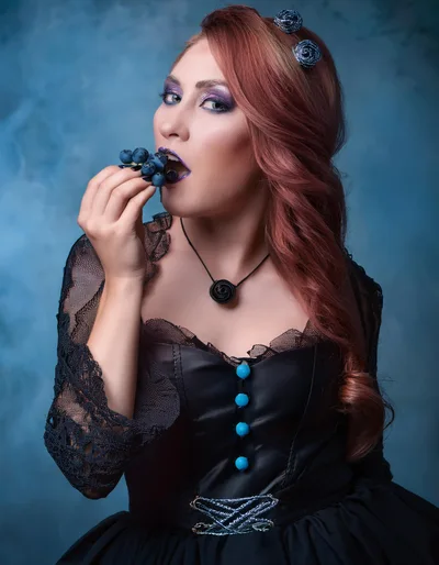 Gothic Woman Eating Blueberries In Studio Portrait