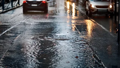 Rainy City Street With Puddles And Car Traffic