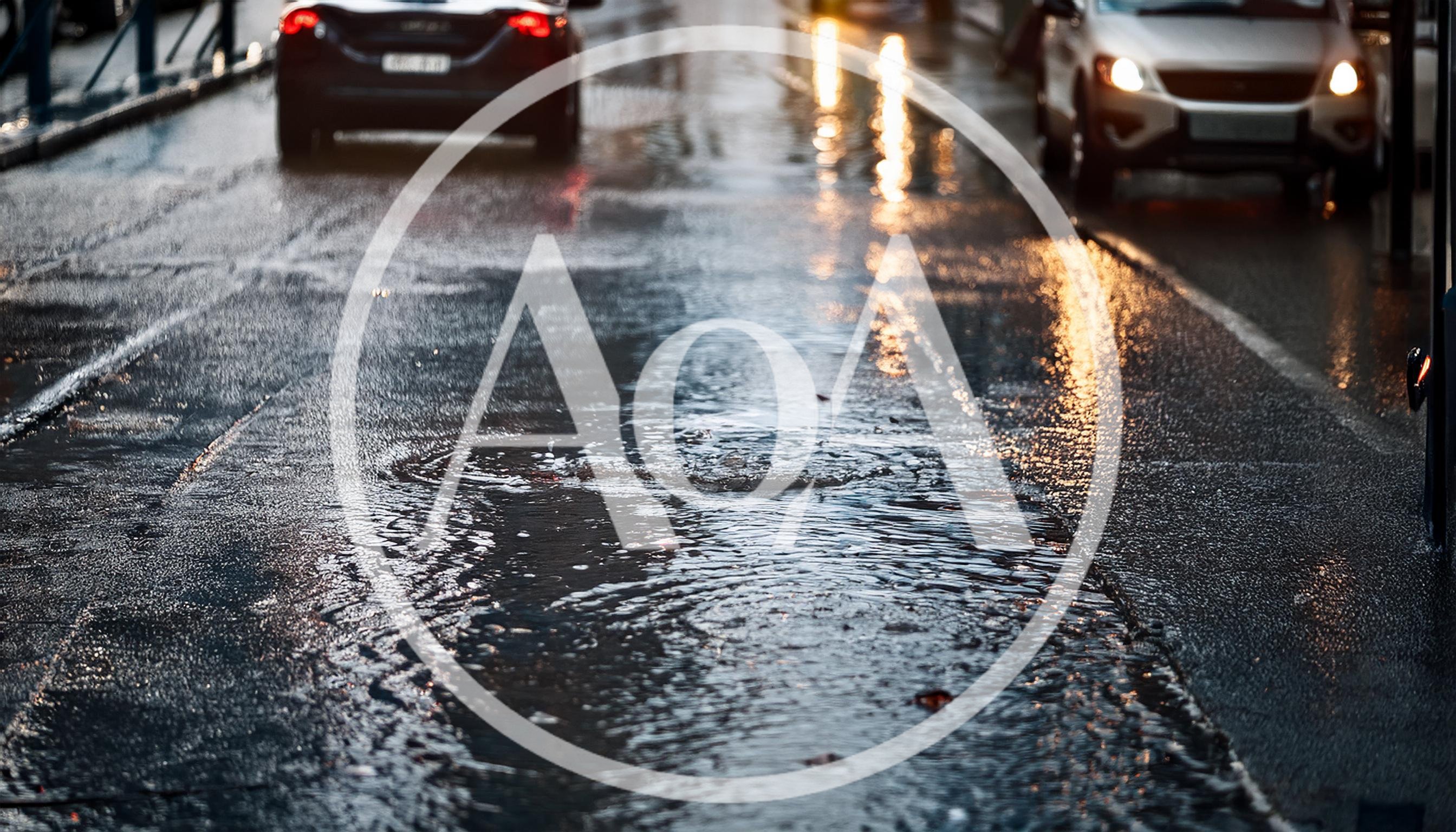 Rainy City Street With Puddles And Car Traffic