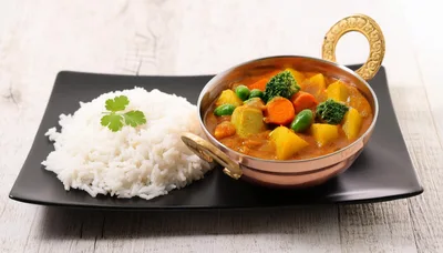 Vegetable Curry With Steamed Rice On A Black Plate