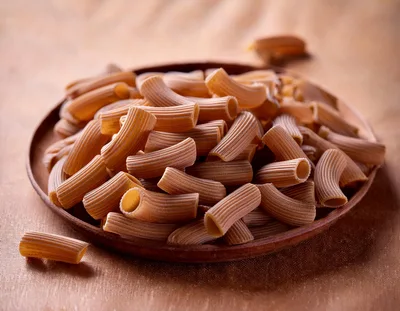 Whole Wheat Rigatoni Pasta On A Wooden Plate