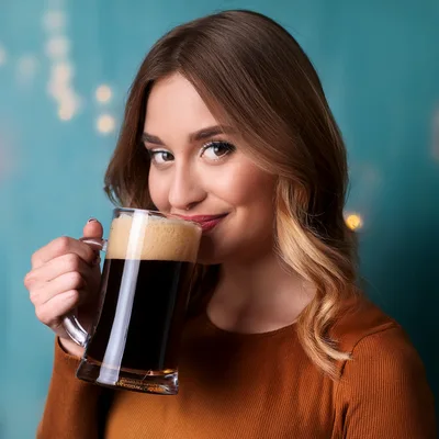 Young Woman Drinking Dark Beer From A Glass Mug