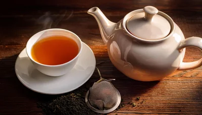 Steaming Cup Of Tea With Teapot And Infuser