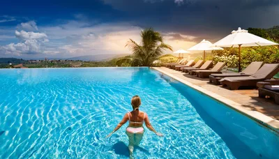 Woman Relaxing In An Infinity Pool At Sunset