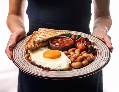 Person Holding A Plate Of Breakfast Food