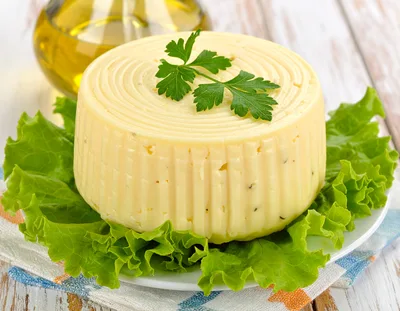 Round Wheel Of Fresh Cheese On Lettuce Leaves