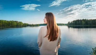 Young Woman Standing By A Calm Forest Lake