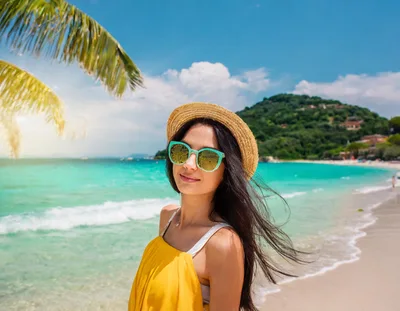 Young Woman Wearing Straw Hat And Sunglasses On Beach