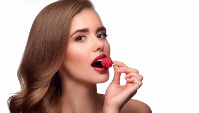Beautiful Woman Holding A Fresh Raspberry To Her Lips