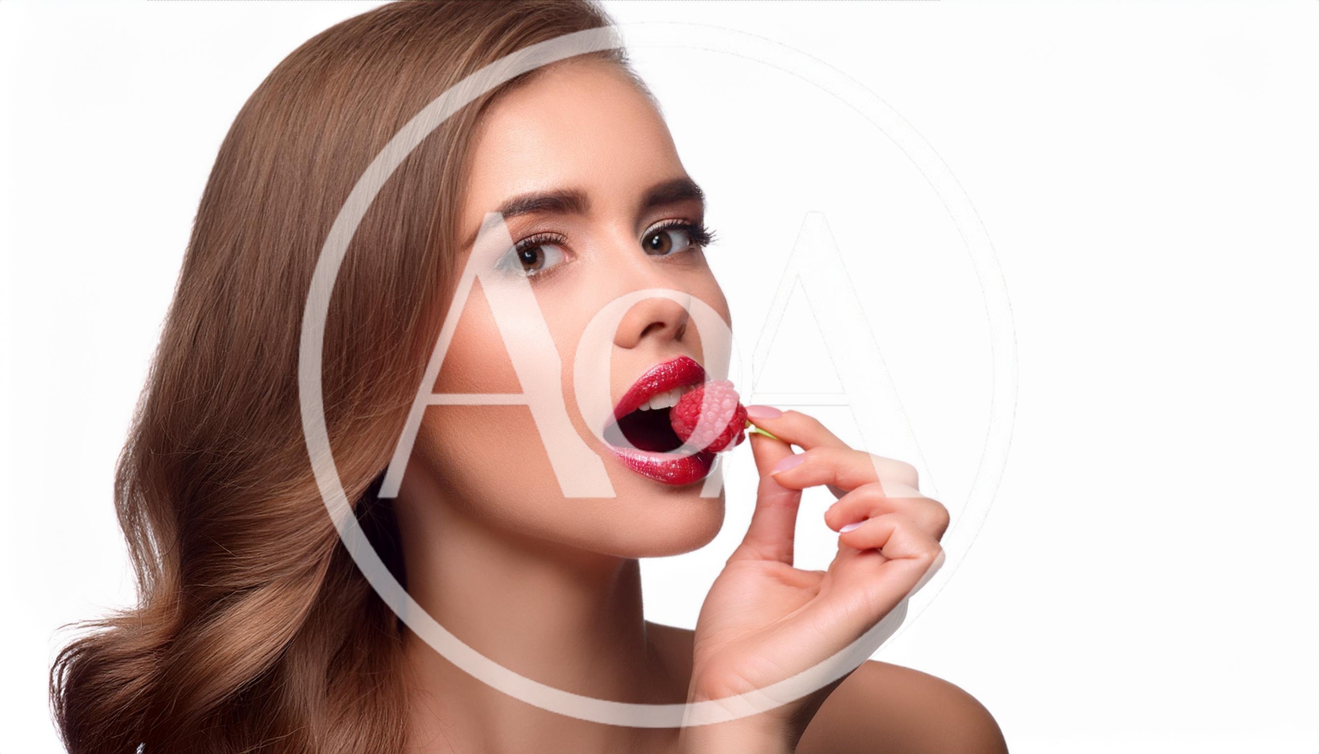 Beautiful Woman Holding A Fresh Raspberry To Her Lips
