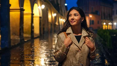 Young Woman Walking Through Rainy European City Street