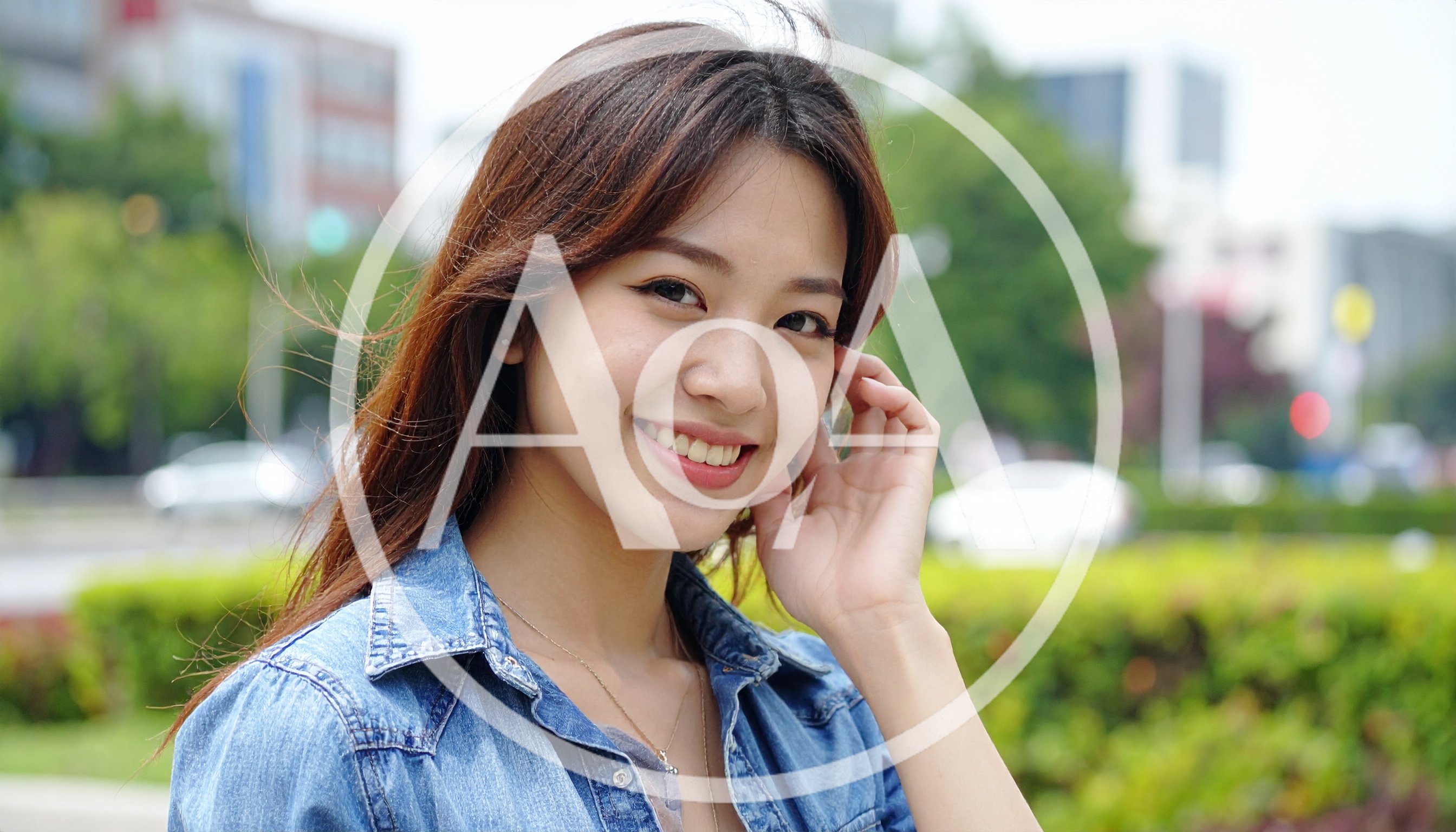 Young Asian Woman Smiling Outdoors In Denim Shirt