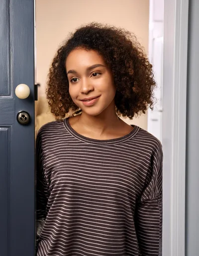 Young Woman Opening A Door To Welcome Guests