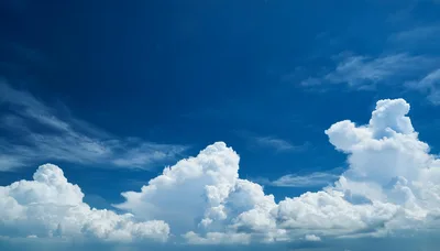 Fluffy White Cumulus Clouds Against Deep Blue Sky