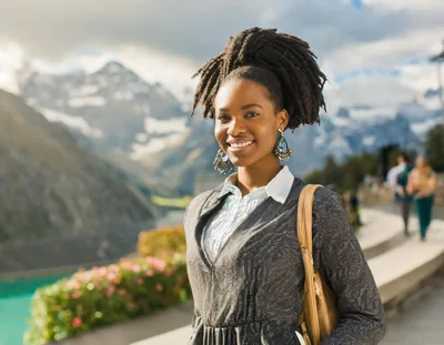 Smiling Young Woman With Dreadlocks In Mountain Landscape