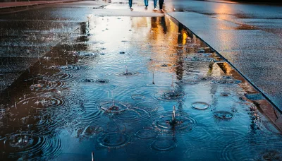 Raindrops Falling Into A Puddle On City Pavement