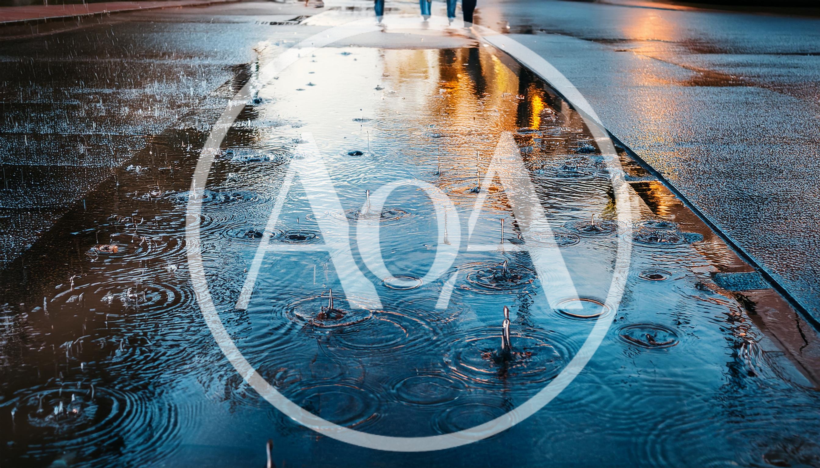 Raindrops Falling Into A Puddle On City Pavement