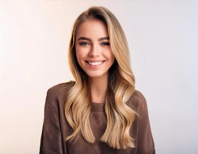 Portrait Of A Smiling Blonde Woman In Brown Sweater